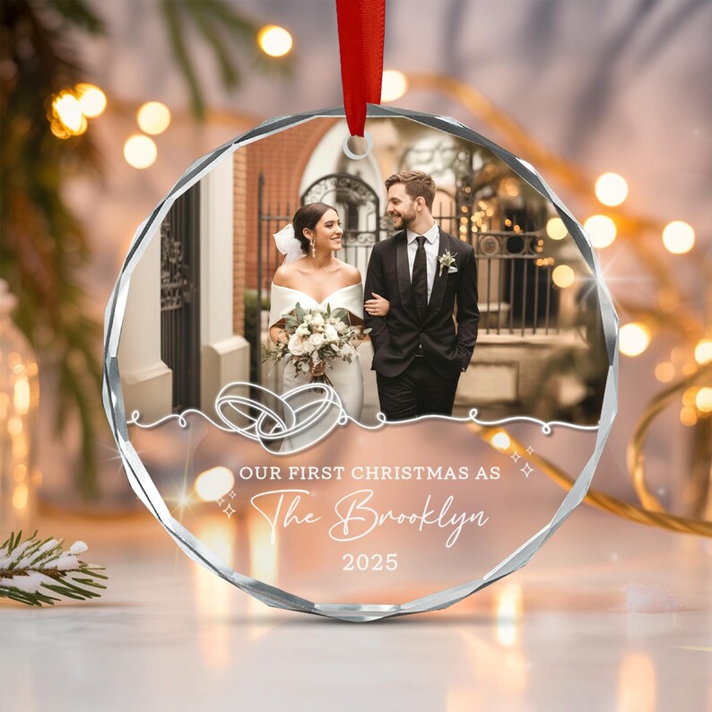 A round, faceted glass Christmas ornament featuring a printed photograph of a couple in wedding attire.