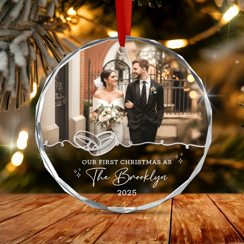A circular, faceted glass Christmas ornament featuring a printed photograph of a couple in wedding attire.