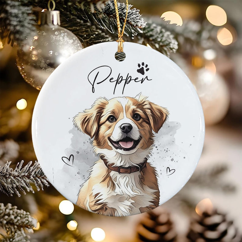 A round white ceramic ornament featuring a colorful illustration of a brown and white dog with a dark collar. The name Pepper is printed in black script above the dog, accompanied by a small paw print and two heart outlines.