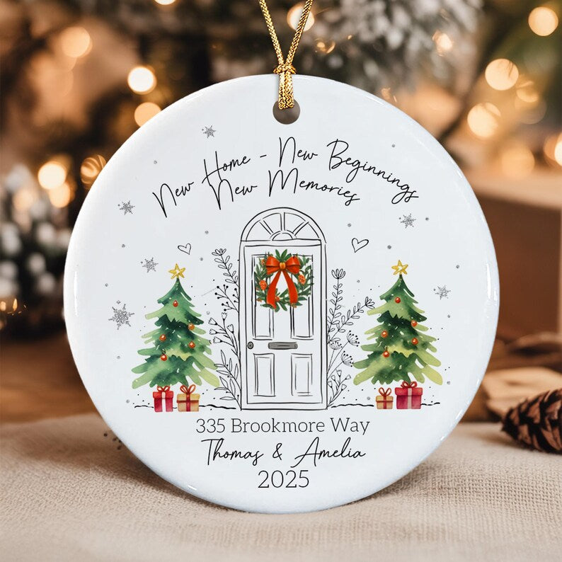 A round white ceramic Christmas ornament featuring a black line drawing of a front door with a red wreath, flanked by two watercolor-style green Christmas trees with red gifts.