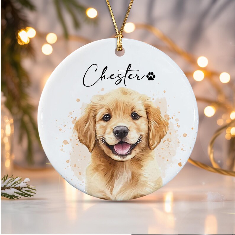 A round white ceramic ornament featuring a watercolor-style illustration of a golden puppy. The name Chester is printed in black script above the puppy, accompanied by a small black paw print icon.