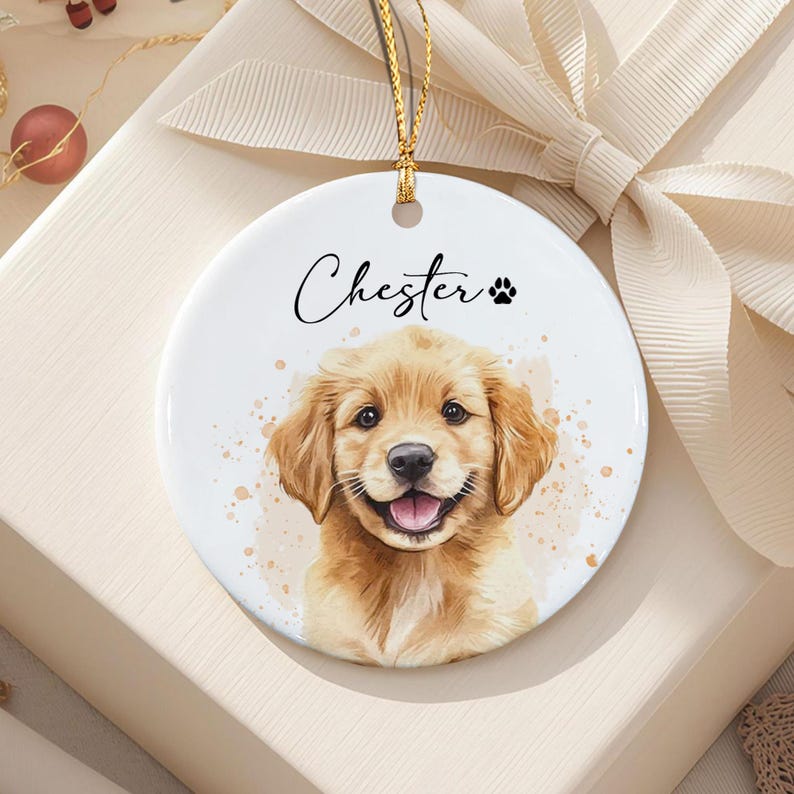 A round white ceramic ornament featuring a watercolor-style illustration of a golden retriever puppy with its mouth open. The name Chester is printed in black script above the puppy, accompanied by a small black paw print icon.
