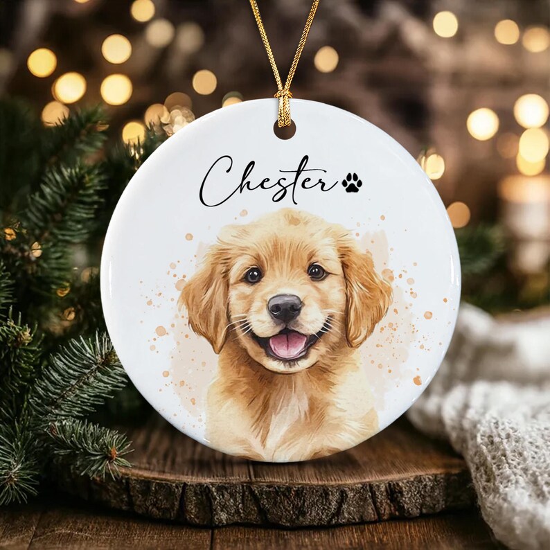 A round white ceramic ornament featuring a watercolor-style illustration of a golden retriever puppy.