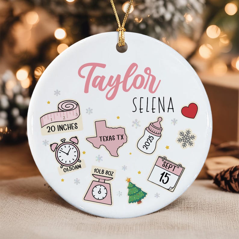 A white circular ceramic ornament with a gold string, featuring the names Taylor and Selena.