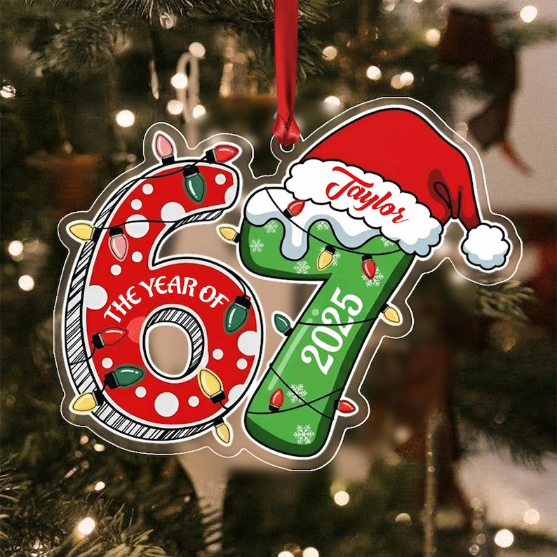 A flat Christmas ornament shaped like the number 67. The red number 6 features white polka dots and the text THE YEAR OF. The green number 7 is topped with a Santa hat labeled Taylor and the year 2025.