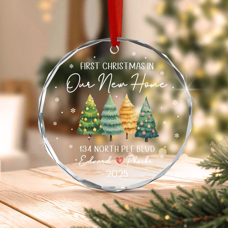 A round, faceted clear glass ornament hanging from a red ribbon.
