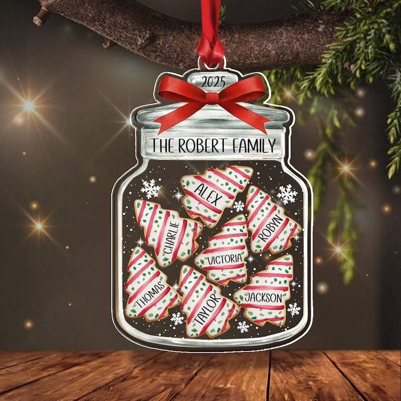 A jar-shaped Christmas ornament featuring a red ribbon bow at the top with the year 2025. The jar is labeled THE ROBERT FAMILY and contains six tree-shaped cookies with red and white stripes, each personalized with names.