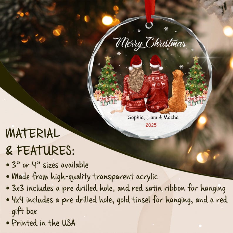 A round, transparent acrylic Christmas ornament featuring a printed illustration of two people and a golden dog sitting before two decorated Christmas trees. The text reads Merry Christmas, Sophia, Liam & Mocha, and the year 2025.