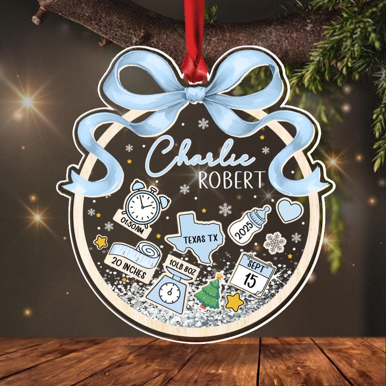 A personalized baby ornament with the name "Charlie Robert" in blue script. The ornament includes baby stats: 20 inches, 10lb 8oz, 01:50AM, and the date September 15, 2025. A blue ribbon tops the ornament.