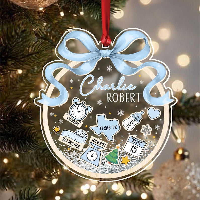 A personalized Christmas ornament with a light blue bow and red ribbon. The ornament features the name "Charlie Robert", along with birth details: 20 inches, 10lb 8oz, 01:50 AM, Texas TX, and the date September 15, 2025.