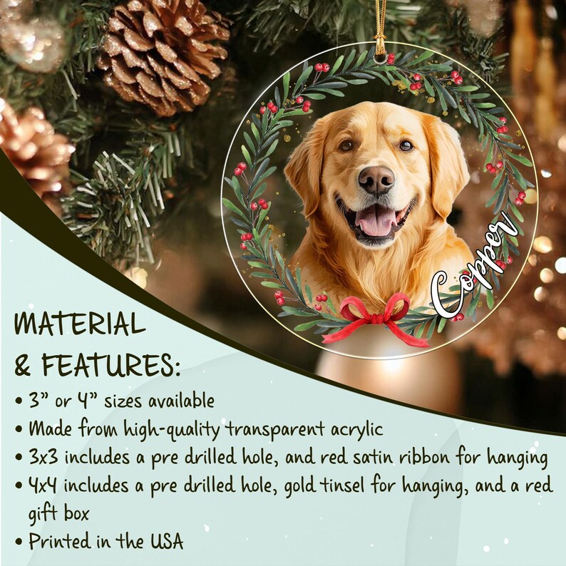 A round transparent acrylic Christmas ornament featuring a portrait of a golden retriever dog centered within a green wreath with red berries and a red bow at the bottom.