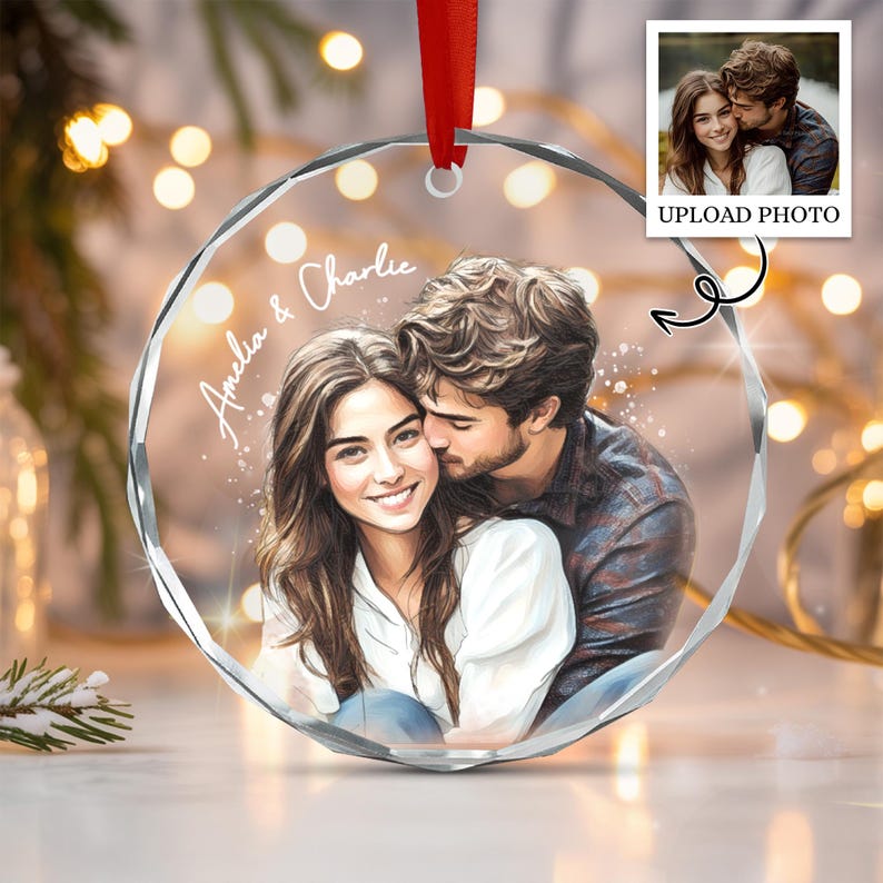 A circular, faceted glass ornament featuring a printed illustration of a couple embracing, with the text "Amelia & Charlie" in white script.