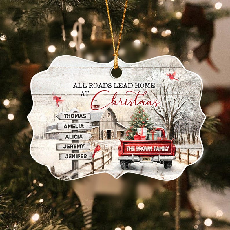 A decorative ornament featuring a winter scene with a red truck carrying gifts, a barn, and a signpost with the names Thomas, Amelia, Alicia, Jeremy, and Jenifer.