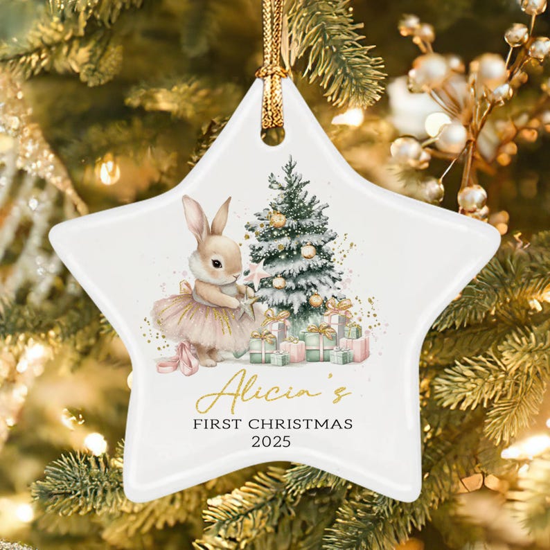A white star-shaped ceramic ornament featuring a watercolor illustration of a rabbit in a tutu standing by a decorated Christmas tree with gifts.