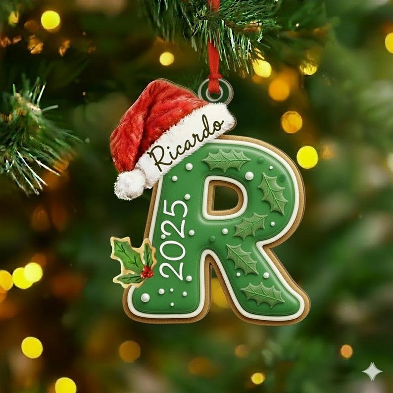A gingerbread-style Christmas ornament shaped like the letter R, featuring a green icing finish with holly leaf patterns, white dots, and the year 2025. A red Santa hat sits atop the letter with the name Ricardo written in script.