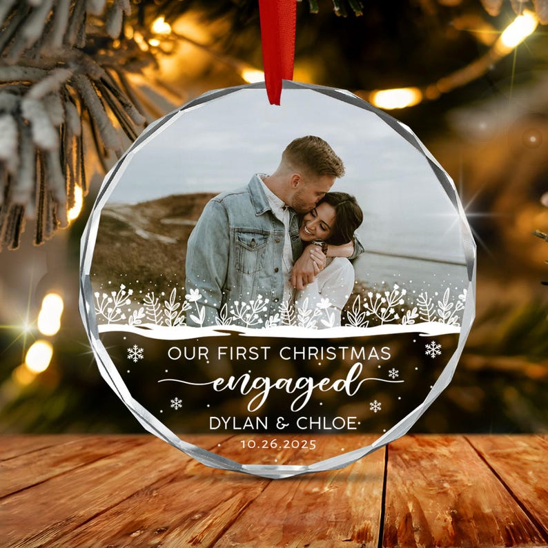 A round, faceted glass Christmas ornament featuring a photograph of a couple embracing outdoors.