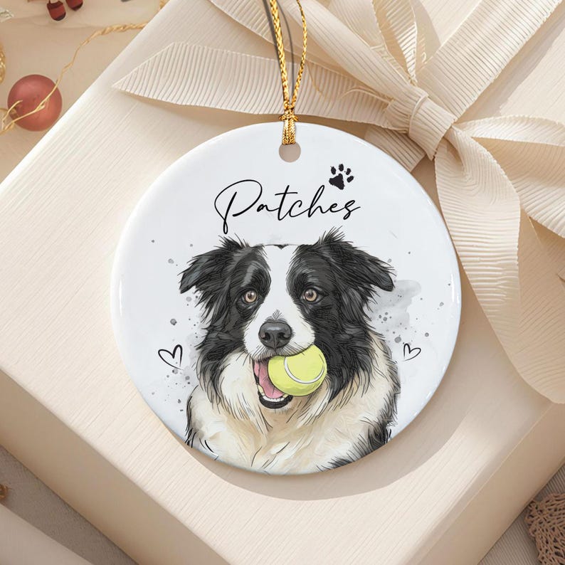 A round white ceramic ornament featuring a black and white Border Collie illustration holding a yellow tennis ball in its mouth.