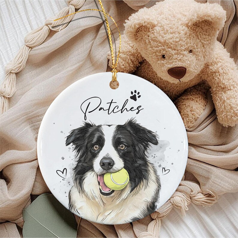 A round white ceramic ornament featuring a black and white border collie illustration with a yellow tennis ball in its mouth. The name Patches is printed in black script above the dog, accompanied by a small black paw print icon.