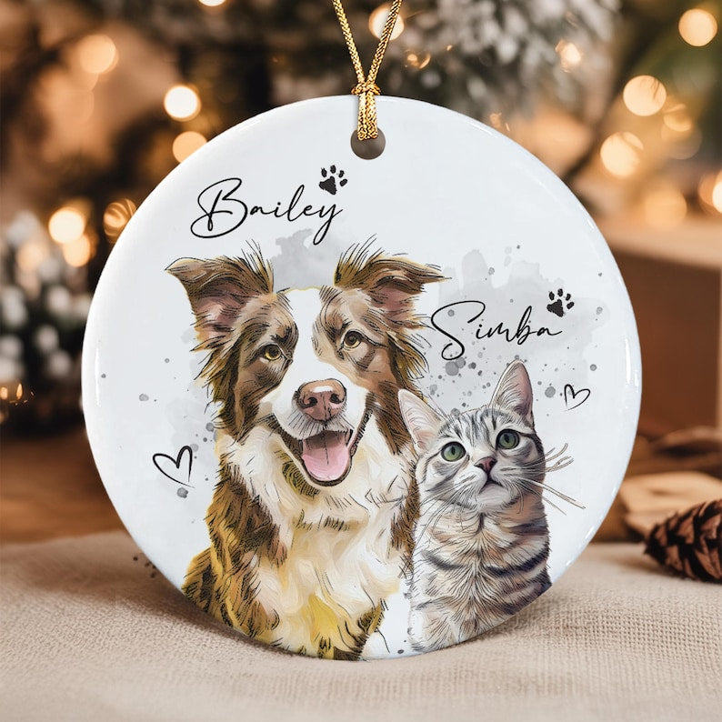 A round white ceramic ornament featuring a colorful illustration of a brown and white dog and a grey tabby cat.