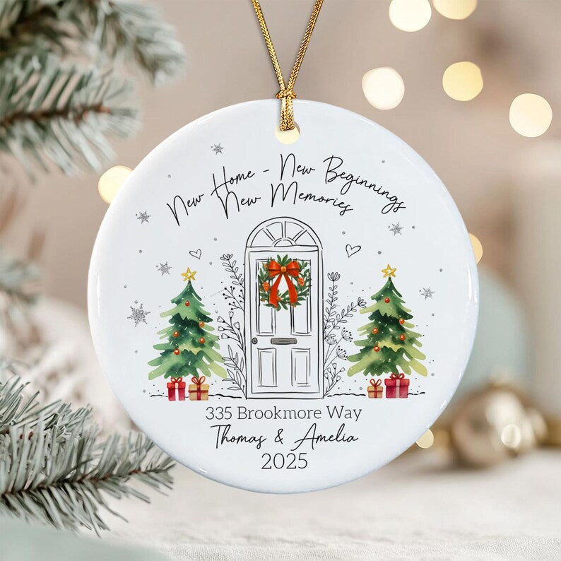 A round white ceramic ornament featuring a line drawing of a front door with a wreath, flanked by two watercolor Christmas trees with gifts.