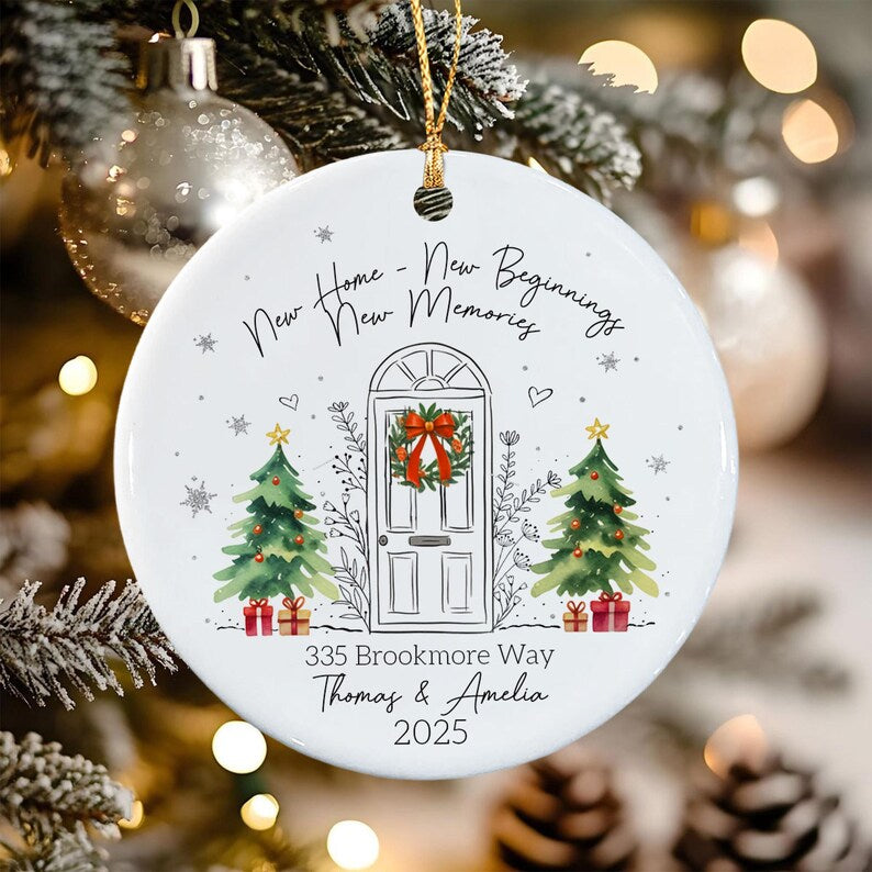 A round white ceramic Christmas ornament featuring a line drawing of a front door with a wreath, flanked by two green Christmas trees with red gifts.