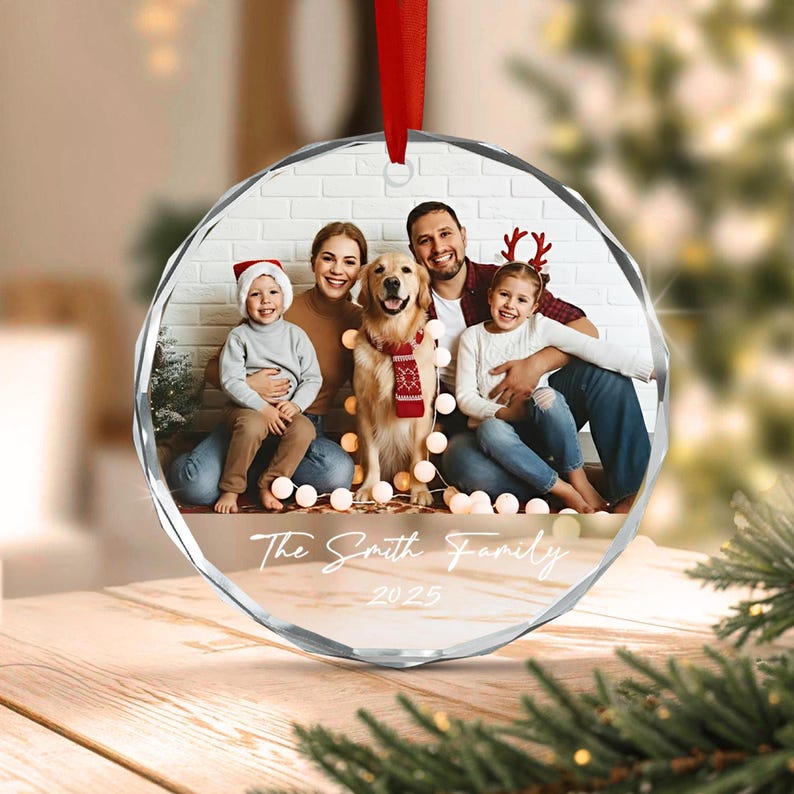 A circular, faceted glass ornament featuring a printed photograph of a family with a dog. The image shows two adults, two children, and a golden retriever wearing a red scarf.