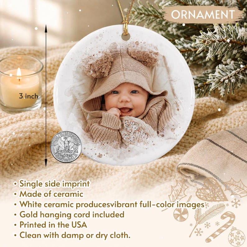 A round white ceramic ornament featuring a full-color photograph of a baby wearing a tan hooded sweater. The ornament includes a gold hanging cord and measures 3 inches in diameter, as indicated by a visible measuring line.