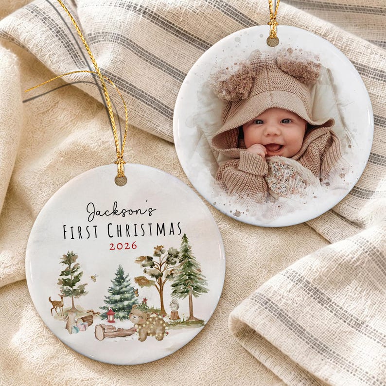 Two round white ceramic ornaments with gold hanging strings. One ornament features a photograph of a baby in a tan hooded sweater.