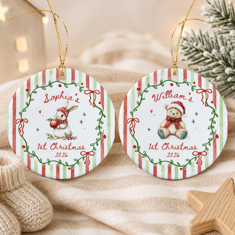 Two round ceramic Christmas ornaments with gold hanging strings. One features a rabbit in a red hat with the text 'Sophia's 1st Christmas 2026', the other a teddy bear in a red hat with 'William's 1st Christmas 2026'.