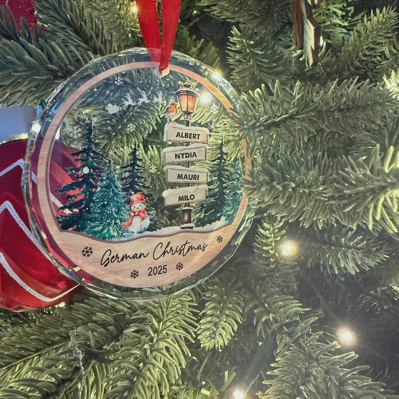 A round, clear glass Christmas ornament hanging by a red ribbon.