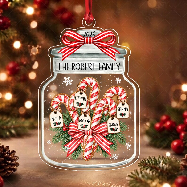 A clear, jar-shaped Christmas ornament featuring a red and white striped bow at the top with the year 2026. The text reads THE ROBERT FAMILY.