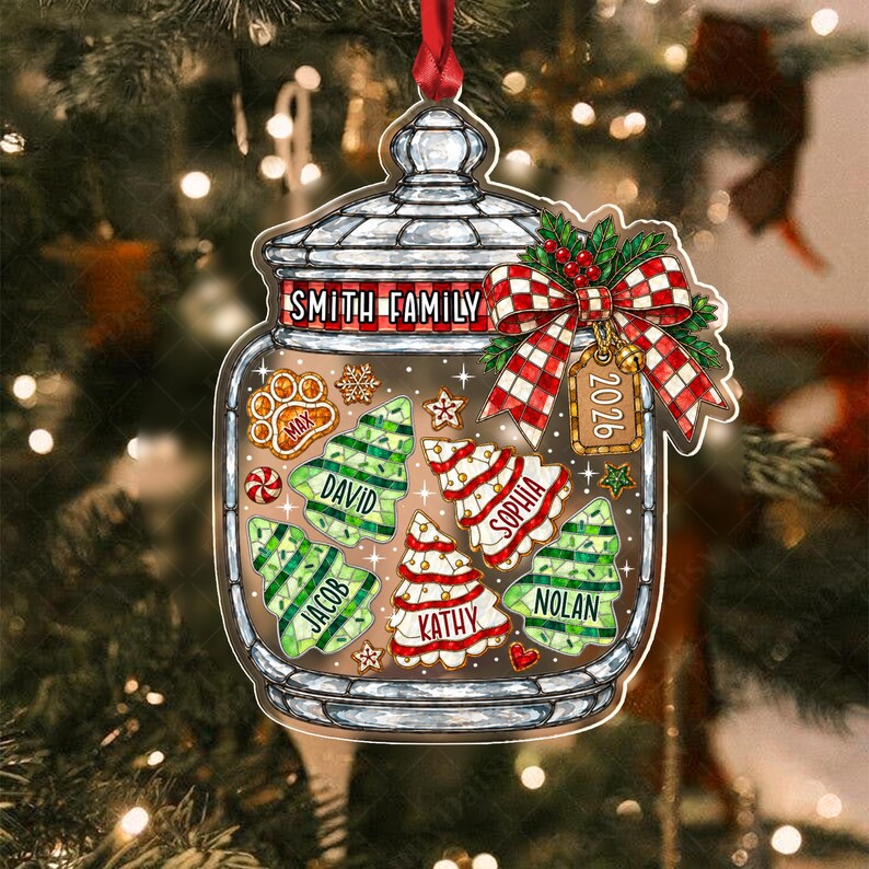 A flat, jar-shaped Christmas ornament featuring a red and white checkered bow, a tag labeled 2026, and the text Smith Family. Inside the jar are illustrated cookies shaped like trees and a paw print, each personalized with names.