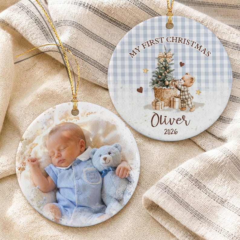 Two round ceramic ornaments with gold hanging strings. One features a photo of a sleeping baby in a blue outfit holding a blue teddy bear.