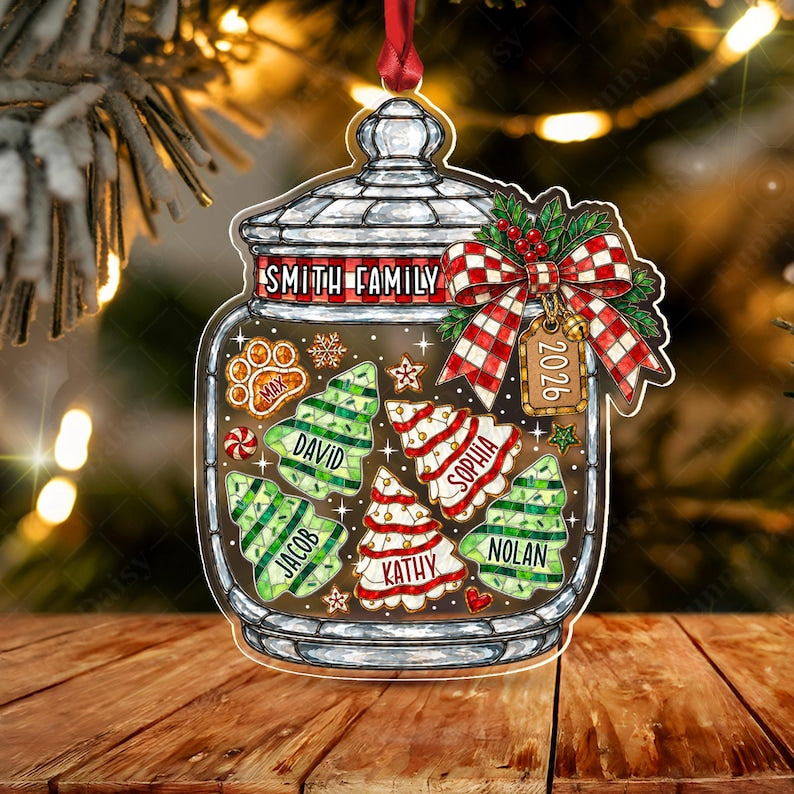 A clear glass jar ornament featuring a red and white checkered bow, a tag labeled 2026, and the text Smith Family. Inside are green and white tree-shaped cookies labeled Max, David, Jacob, Sophia, Kathy, and Nolan.