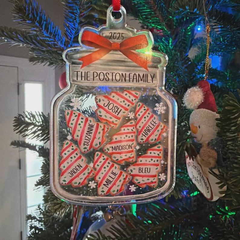 A clear acrylic jar-shaped Christmas ornament featuring a red ribbon at the top with the year 2025.