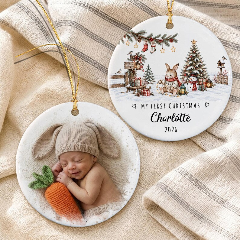 Two round ceramic ornaments with gold hanging strings. One features a sleeping baby wearing a bunny ear hat holding a crocheted orange carrot.