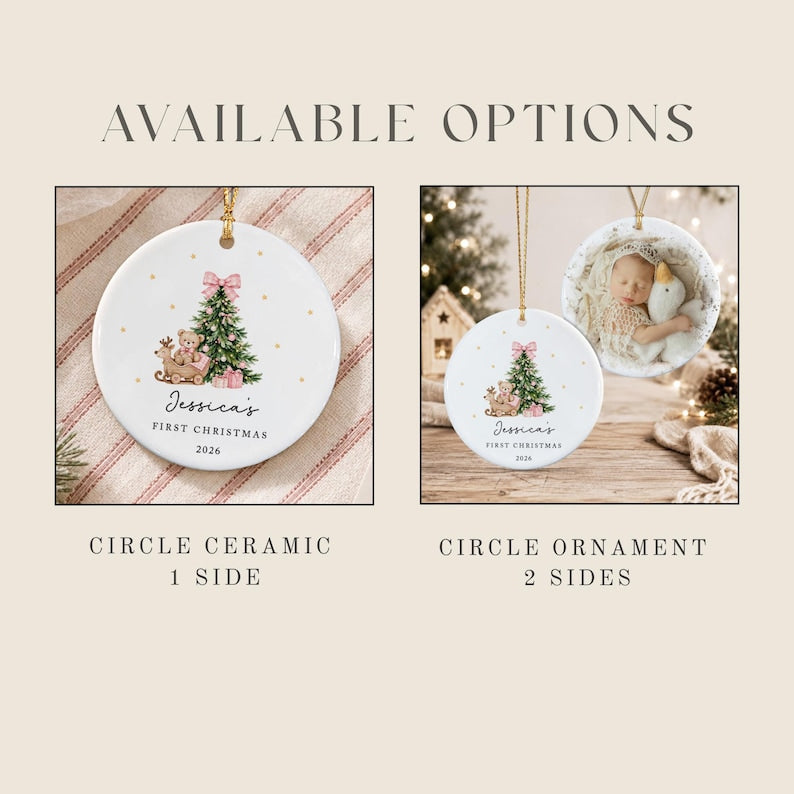 Two round white ceramic ornaments with gold hanging strings. One shows a Christmas tree, a teddy bear in a sleigh, and the text 'Jessica's FIRST CHRISTMAS 2026'.