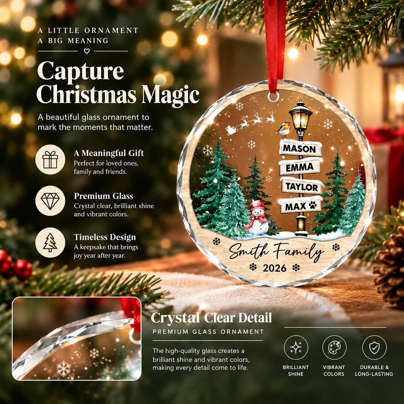 A round glass Christmas ornament featuring a printed winter scene with a street lamp, evergreen trees, a snowman, and a flying sleigh. The signpost displays the names Mason, Emma, Taylor, and Max, with Smith Family and 2026 below.